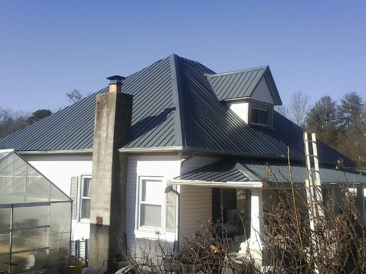 Dark blue standing seam metal roof on a white farmhouse with dormer — Slate & Tile Roof Repair by Roofing Brothers in Snow Camp