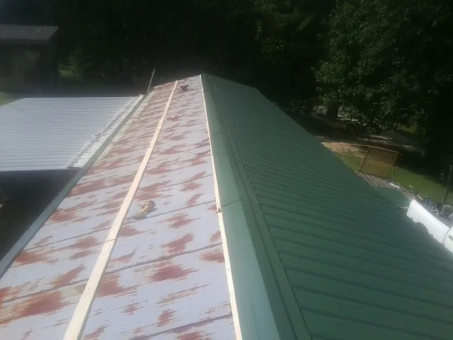 Old rusted panels beside newly installed green metal roofing — Wind Damage Roof Repair by Roofing Brothers in Snow Camp