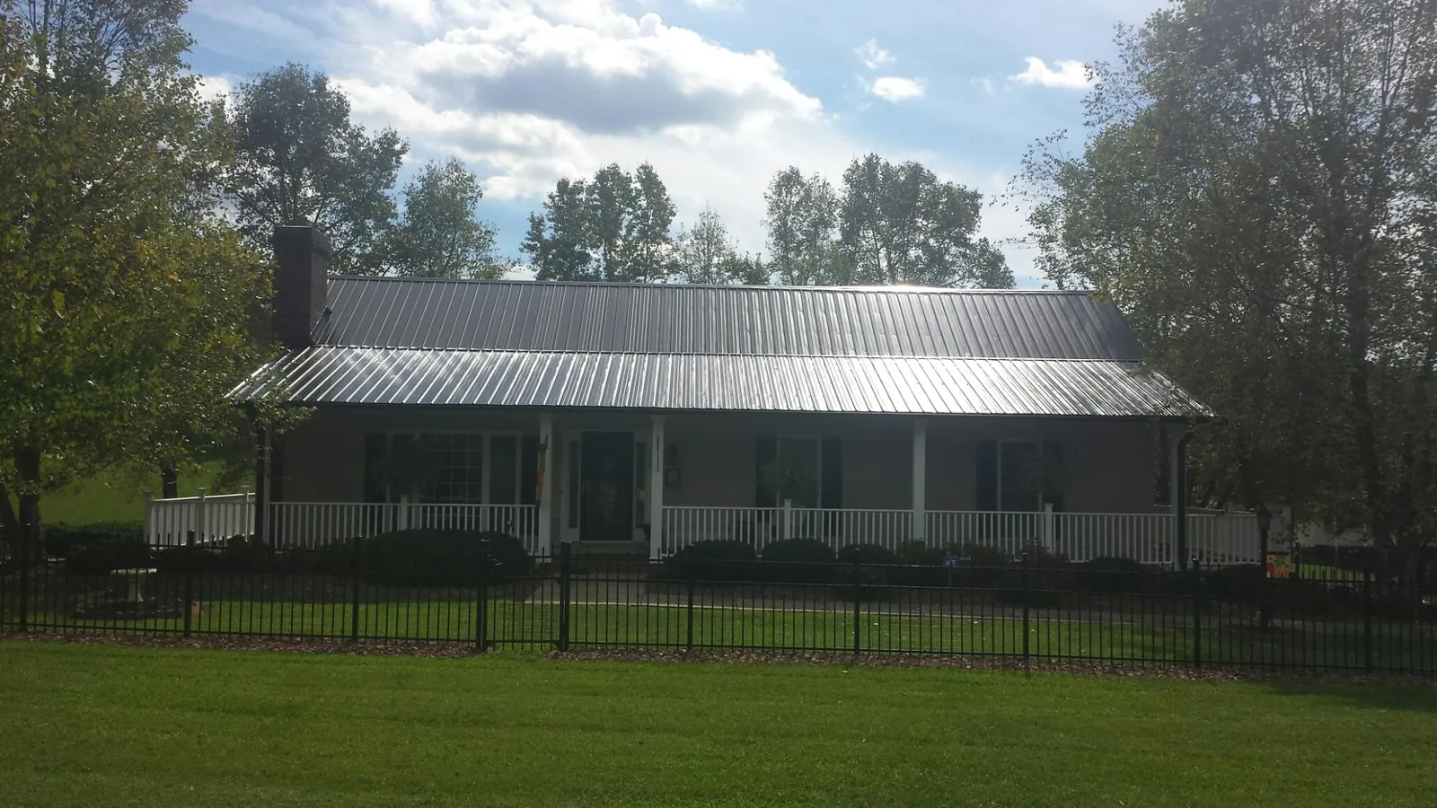 Gray metal roof on a brick ranch with a full width front porch — Gutter Guard Installation work by our crew in Snow Camp