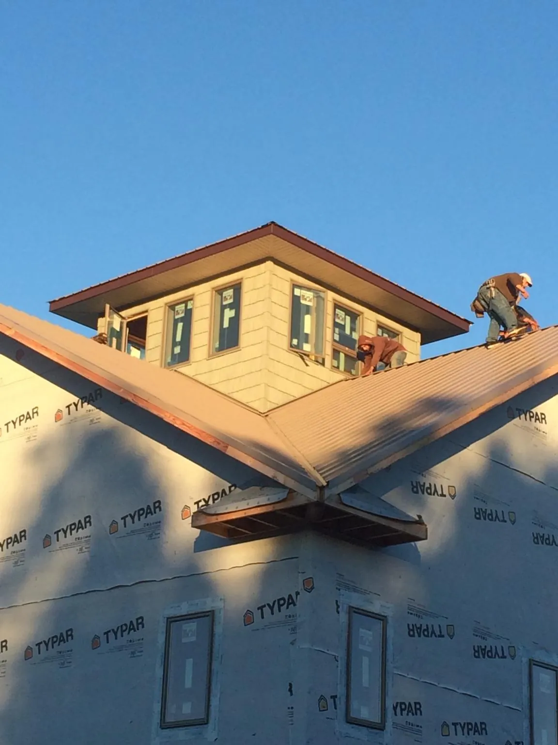 Roofers working around a rooftop cupola on a new metal roof at sunset — Roof Waterproofing in Snow Camp by Roofing Brothers
